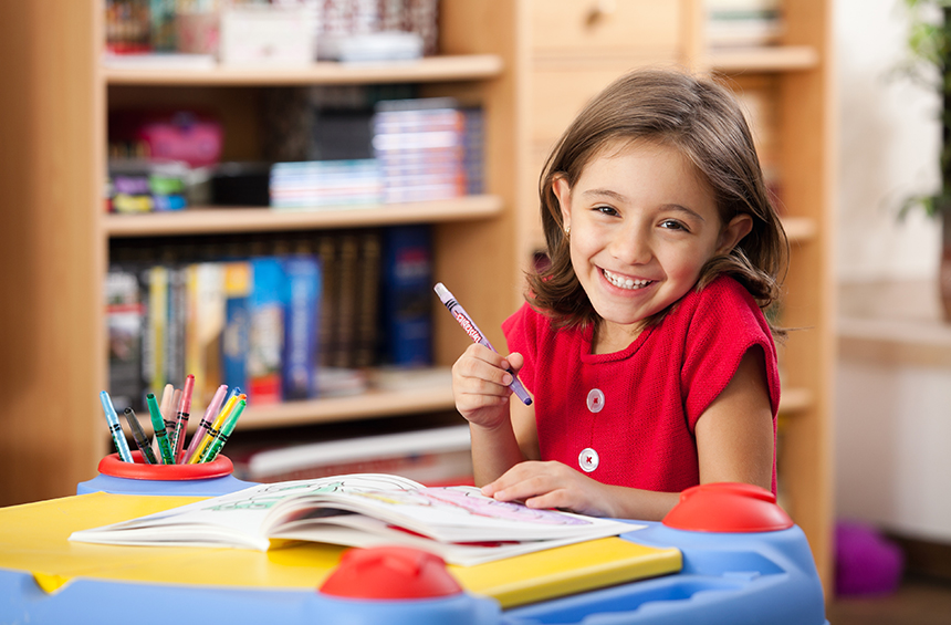 Smiling girl colouring at Play & Stay Family Day Care Goulburn, ready to enrol